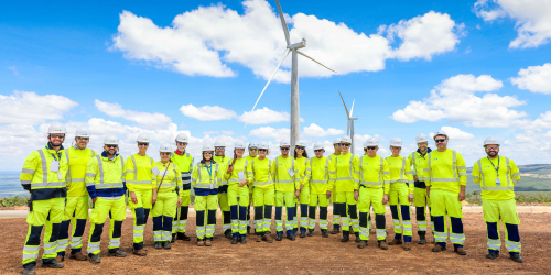 Large group of people standing in front of a wind farm